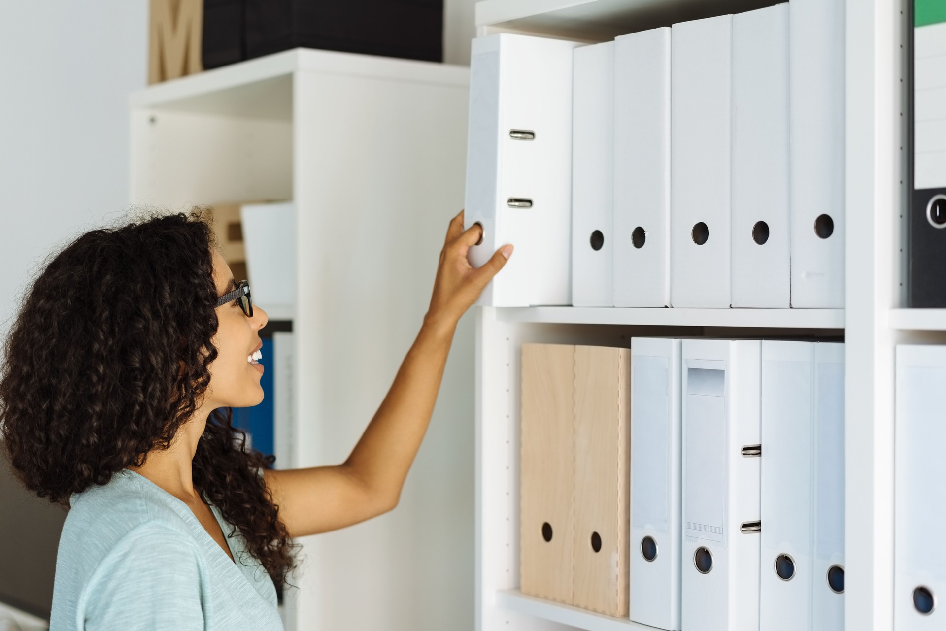 Young office worker taking a file from the shelf